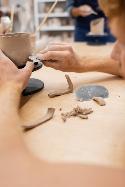 Vista cortada do homem fazendo copo de barro com ferramenta na oficina de cerâmica  - Foto, Imagem