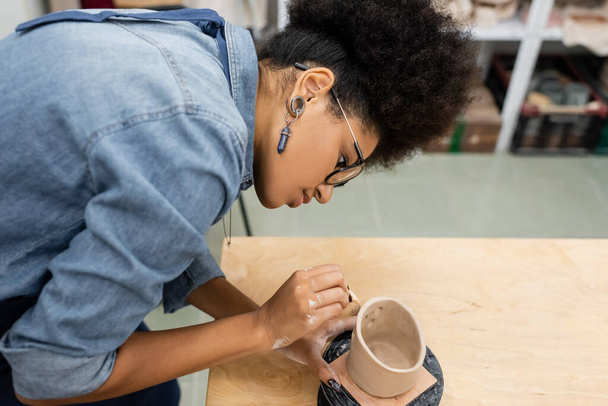 Side view of african american artisan forming ceramic product in pottery studio  - Fotó, kép