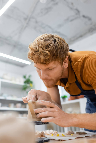 Redhead artigiano in grembiule formando tazza di ceramica in laboratorio di ceramica  - Foto, immagini