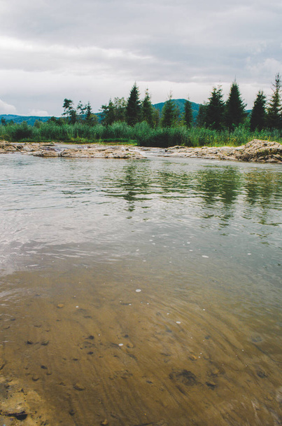 río de montaña entre acantilados. agua azul clara del río. Hojas verdes jóvenes de árboles en la orilla del río, primavera - Foto, Imagen