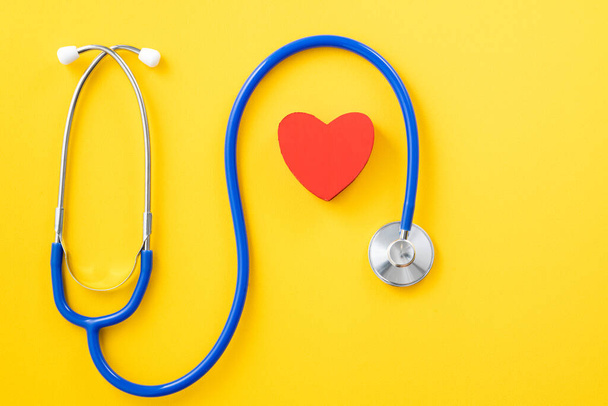 Doctor diagnoses and care design concept - stethoscope with red heart on yellow background. - Valokuva, kuva