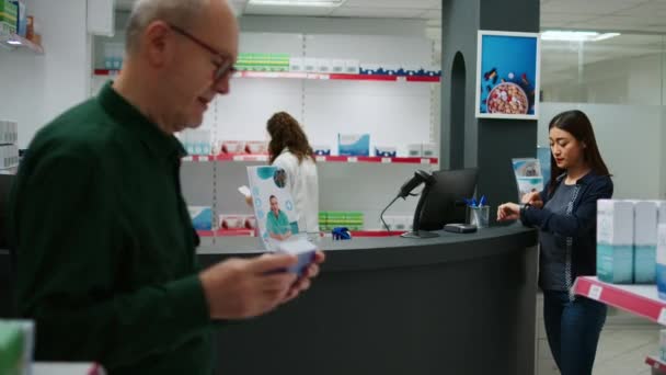 Mujer comprando pastillas de cardiología y pagando con smartwatch en el mostrador de la farmacia, usando nfc para pagar el tratamiento con receta. Compra de productos y suplementos sanitarios en farmacia. - Metraje, vídeo