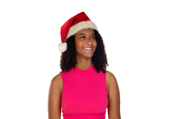 Niña afroamericana joven con sombrero de navidad sobre fondo aislado con camiseta rosa - Foto, imagen
