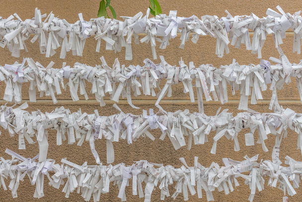 Omikuji, маленькі клаптики паперу з удачею або молитвами написані на них, прив'язані до дротів, в Gojoten shinto храм, Уено, Токіо, Японія.. - Фото, зображення
