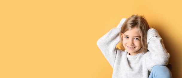 Χαριτωμένο μοντέρνο κορίτσι σε ζεστό πουλόβερ σε πορτοκαλί φόντο με χώρο για κείμενο - Φωτογραφία, εικόνα