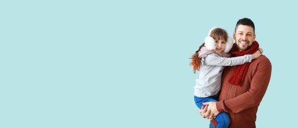 Cute little girl and father in winter clothes on light blue background with space for text - Photo, Image