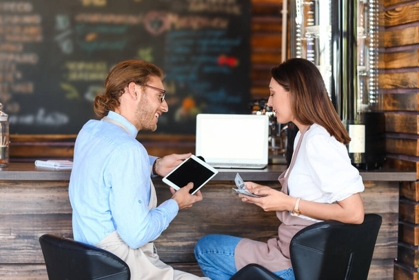 Geschäftsinhaber arbeiten mit Tablet-Computer am Tisch in ihrem Café - Foto, Bild