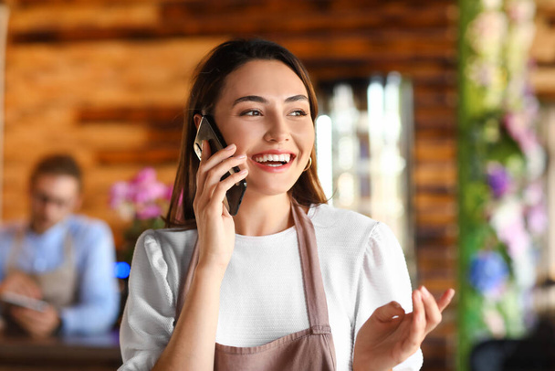 Propietaria mujer de negocios hablando por teléfono móvil en su cafetería - Foto, imagen