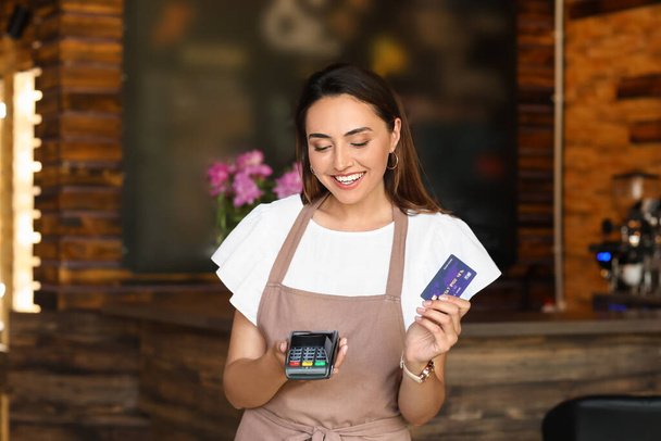 Piękny właściciel firmy z terminalem płatniczym i kartą kredytową w kawiarni - Zdjęcie, obraz