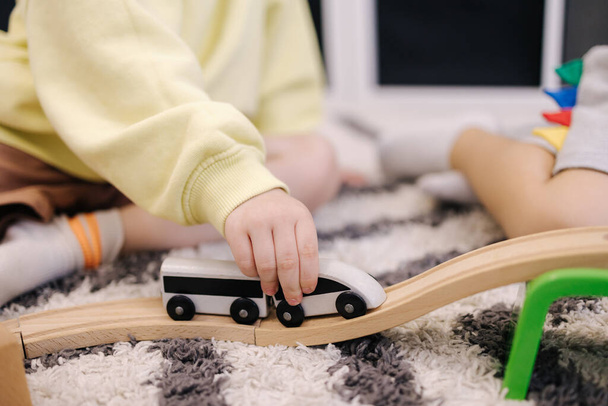 Mały chłopiec trzyma zabawkowy pociąg w rękach i jeździ nim na drewnianej poręczy.. - Zdjęcie, obraz