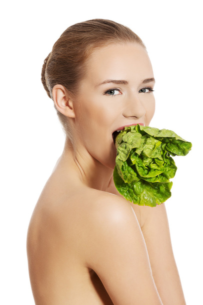 Side view of nude woman eating lettuce - Fotoğraf, Görsel