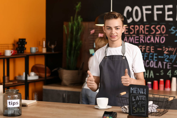 Νεαρό αρσενικό barista με φλιτζάνι καφέ στο καφέ - Φωτογραφία, εικόνα