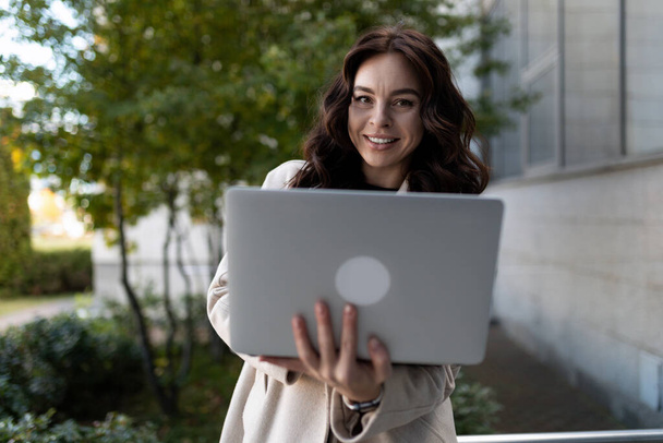 élégant jeune femme d'affaires avec un ordinateur portable dans ses mains dans le contexte d'un immeuble de bureaux. - Photo, image