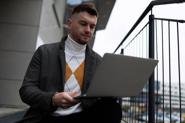 portré egy fiatal üzletemberről laptoppal az irodán kívül. - Fotó, kép