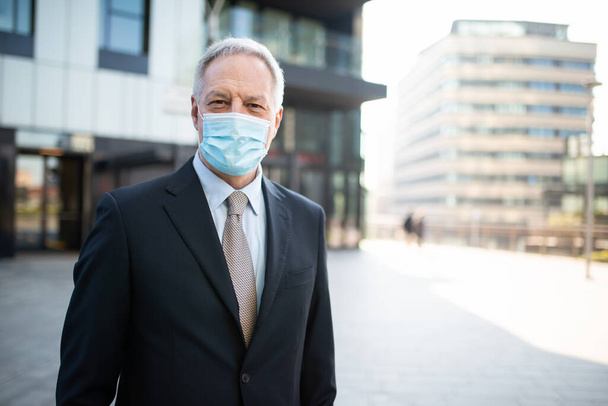 Gerente sênior vestindo uma máscara protetora ao ar livre contra Covid 19 - Foto, Imagem