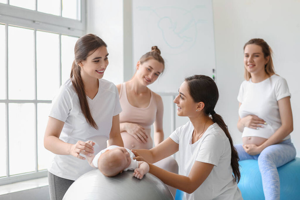 Female coach with baby and pregnant women training in gym - Фото, зображення