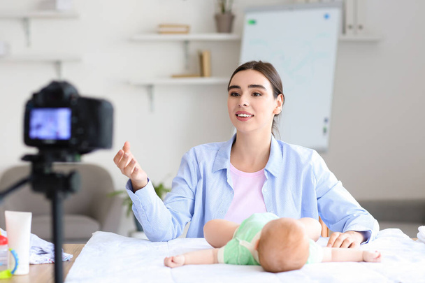 Junge Frau mit kleinem Baby nimmt Videokurs zu Hause auf - Foto, Bild