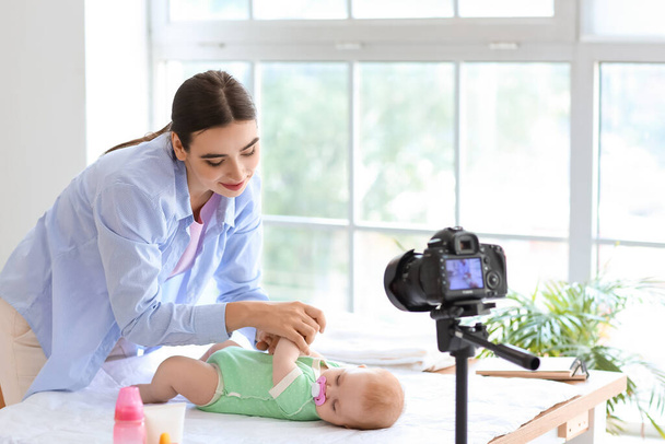 Junge Frau mit kleinem Baby nimmt Videokurs zu Hause auf - Foto, Bild
