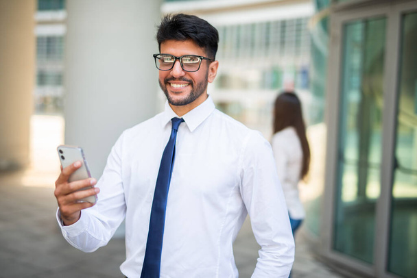 Smiling businessman using his cellphone in front of colleague, teamwork concept - Foto, imagen