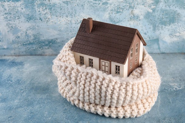 Modello di casa con sciarpa lavorata a maglia su sfondo grunge. Concetto riscaldamento - Foto, immagini