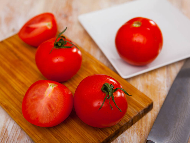 Fresh ripe tomatoes ready for cooking on wooden background at kitchen - Foto, afbeelding