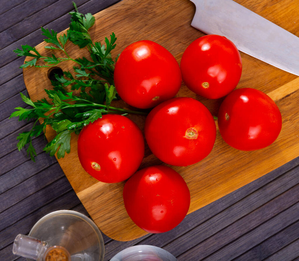 Delicious ripe tomatoes with fresh parsley, lying on a wooden surface. Ingredients for cooking - Фото, зображення