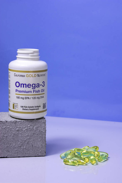 Un frasco de vitaminas omega 3, vitaminas están sobre la mesa, una cuchara de madera con vitaminas omega 3 sobre un fondo azul, el concepto de un estilo de vida saludable, suplementos dietéticos, vitaminas, salud - Foto, Imagen