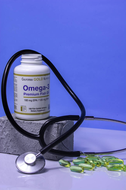 Un frasco de vitaminas omega 3, vitaminas están sobre la mesa, una cuchara de madera con vitaminas omega 3 sobre un fondo azul, el concepto de un estilo de vida saludable, suplementos dietéticos, vitaminas, salud - Foto, Imagen