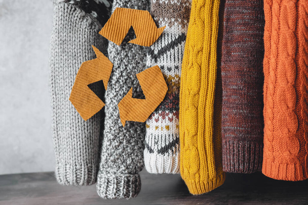 Las mangas de suéteres de punto en una paleta de otoño cuelgan sobre un fondo gris. suéteres usados. Moda ecológica y sostenible. .. Foto de alta calidad - Foto, imagen