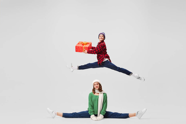Relationships. Creative portrait of ballet dancers in warm clothes and hat dancing, having fun isolated on gray background. Merry Christmas, New year, holidays, 2023, party concept. Winter fashion - Fotografie, Obrázek