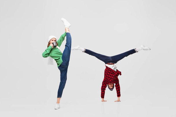 Joy, fun. Creative portrait of ballet dancers in warm clothes and hats dancing, having fun isolated on gray background. Merry Christmas, New year, holidays, 2023, party concept. Winter fashion - Photo, image