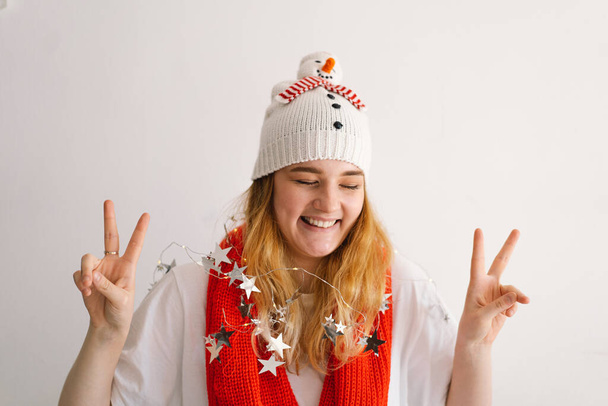 Lustiges junges Mädchen mit Weihnachtsmütze, Schneemann und rotem Schal. Neujahrs- und Weihnachtskonzept. - Foto, Bild