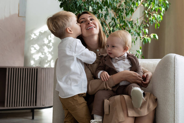 mãe com dois filhos adoráveis um dos quais a beija na bochecha, conceito dia mães. - Foto, Imagem