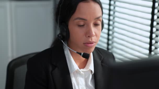 Αρμόδια Αφροαμερικανίδα χειριστής που εργάζεται στον υπολογιστή και ενώ συνομιλεί με πελάτες. Έννοια σχετική τόσο με τα τηλεφωνικά κέντρα όσο και με τα γραφεία εξυπηρέτησης πελατών. - Πλάνα, βίντεο