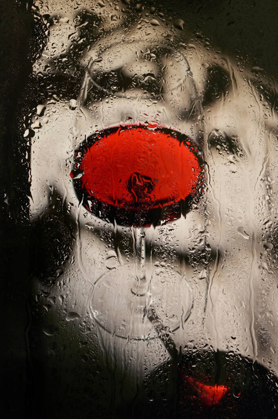 Abstract Glas droge rode wijn door regenachtig venster - Foto, afbeelding