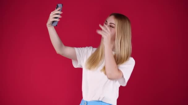 4k-Video einer Teenagerin, die ein Selfie auf rotem Hintergrund macht. Konzept der Influencer. - Filmmaterial, Video