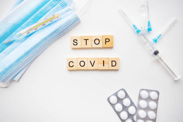 Stop coronavirus inscriptie. Voorbereiding voor vaccinatie tegen covid-19. Spuit, vaccin, pillen, medisch masker - Foto, afbeelding