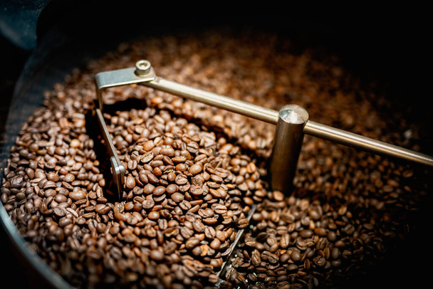Close up machine spatula with brown arabica coffee beans near special equipment. Factory concept. - Foto, immagini