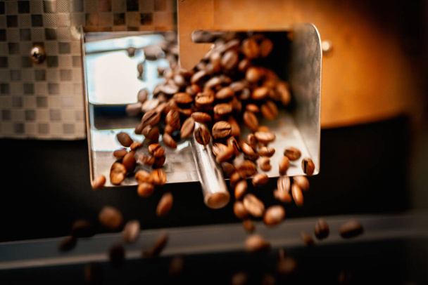 特別な設備の近くに茶色のアラビカコーヒー豆と機械へらを閉じます。工場概念. - 写真・画像