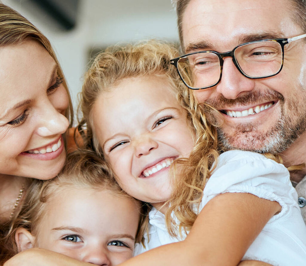 Closeup of a happy Caucasian family of four relaxing in the living room at home. Loving smiling family being affectionate together. Young couple bonding with their little kids at home. - Foto, Bild