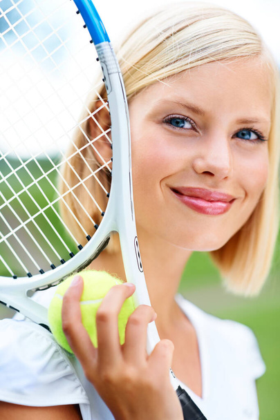 Она любит красоту игры. Портрет молодой теннисистки, держащей мяч и ракетку - Фото, изображение