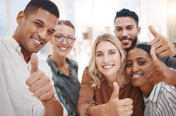 Portrait of a group of confident diverse businesspeople gesturing thumbs up and taking selfies together in an office. Happy colleagues smiling for photos and video call as a dedicated and ambitious t. - Φωτογραφία, εικόνα