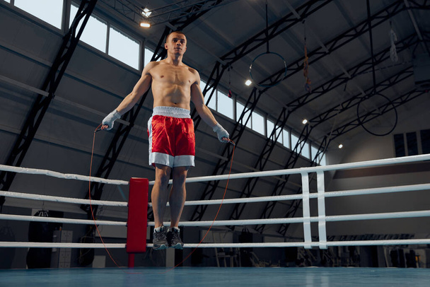 Jumps. Young muscle man, boxer workout at boxing ring at sports gym. Health, motivation and exercise, sport, challenges, strategy. Fight, muscle and workout with sports gloves in mma studio. - Φωτογραφία, εικόνα