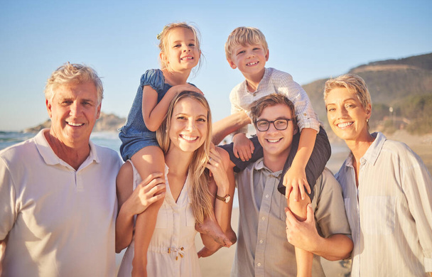 Portrait of a senior caucasian couple at the beach with their children and grandchild. Happy family relaxing on the beach having fun and bonding. - Foto, imagen