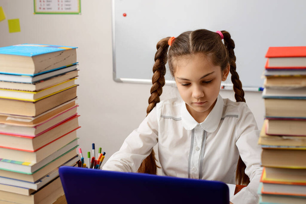 Skoncentrowany uczennica szkoły dziewczęcej przygotowuje się do zajęć, woorking na nowoczesnym laptopie, robi ćwiczenia online, przy użyciu zaawansowanych technologii. Koncepcja wykorzystania nowoczesnych technologii w edukacji, sdudying - Zdjęcie, obraz