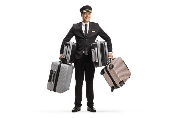 Full length portrait of a smiling bellboy holding many suitcases isolated on white background - Photo, image