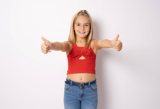 Close-up portrait of her she nice cute adorable lovely sweet cheerful cheery straight-haired blonde pre-teen girl opened mouth showing thumbs up isolated on white background - Фото, изображение