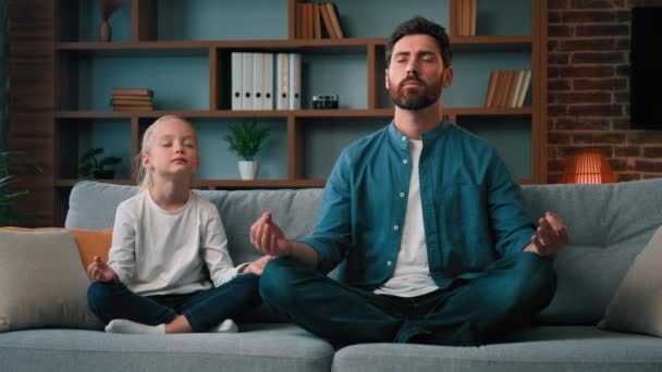Healthy caucasian family practice yoga together sit in lotus pose young father teach little daughter meditate calm down emotions relaxation exercise good life habit at home during quarantine no stress - Footage, Video