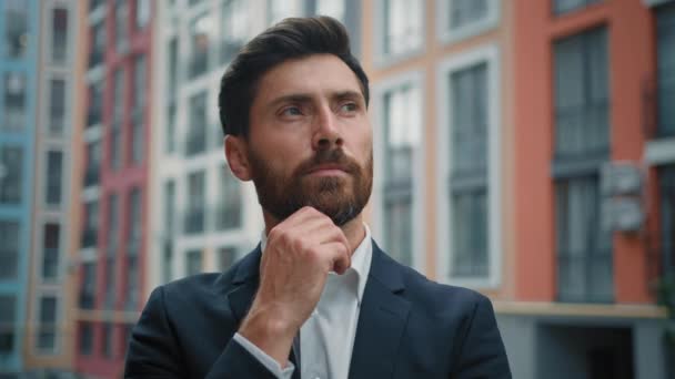 Caucasian smart puzzled thoughtful man hold hand to chin dreaming about career growth successful employer in stylish black suit stand outside modern office pondering idea planning business development - Footage, Video