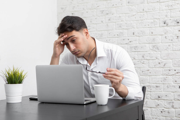 Mladý pohledný podnikatel se cítí špatně poté, co únavné pracovní den online. Koncept vzdálené práce - Fotografie, Obrázek